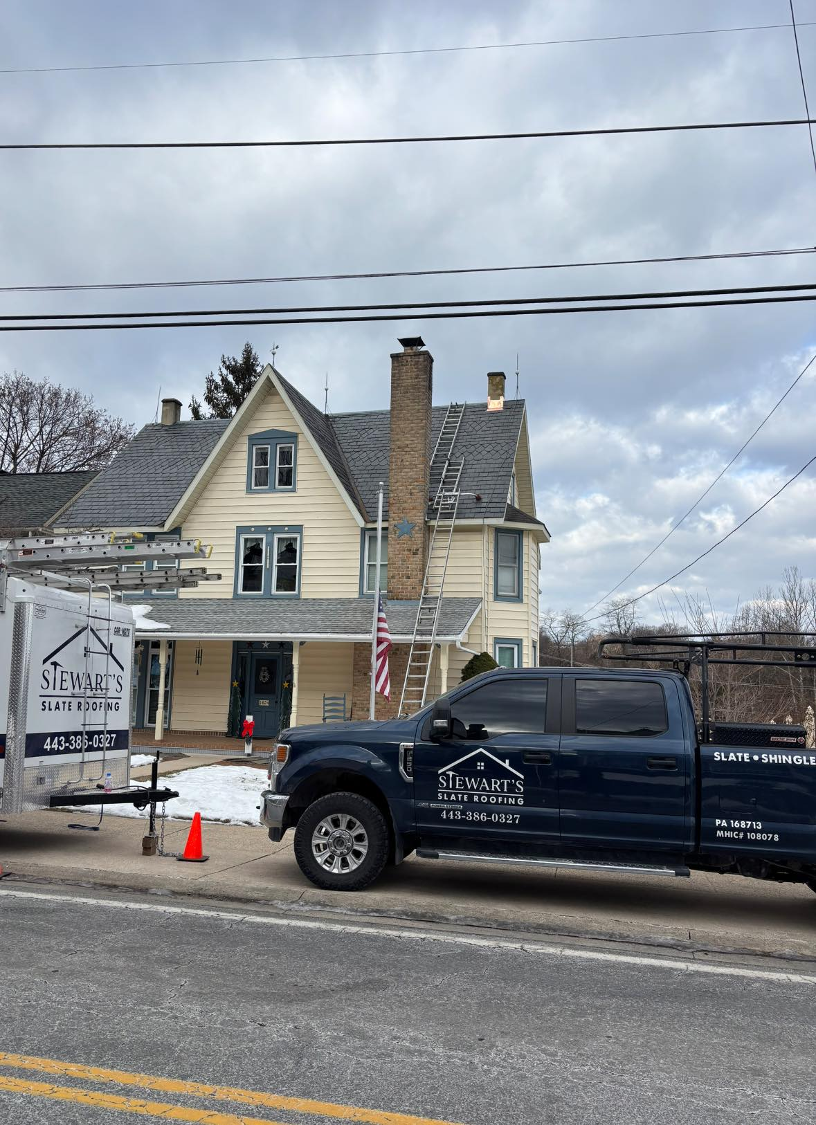 A blue truck is parked on the side of the road in front of a house.