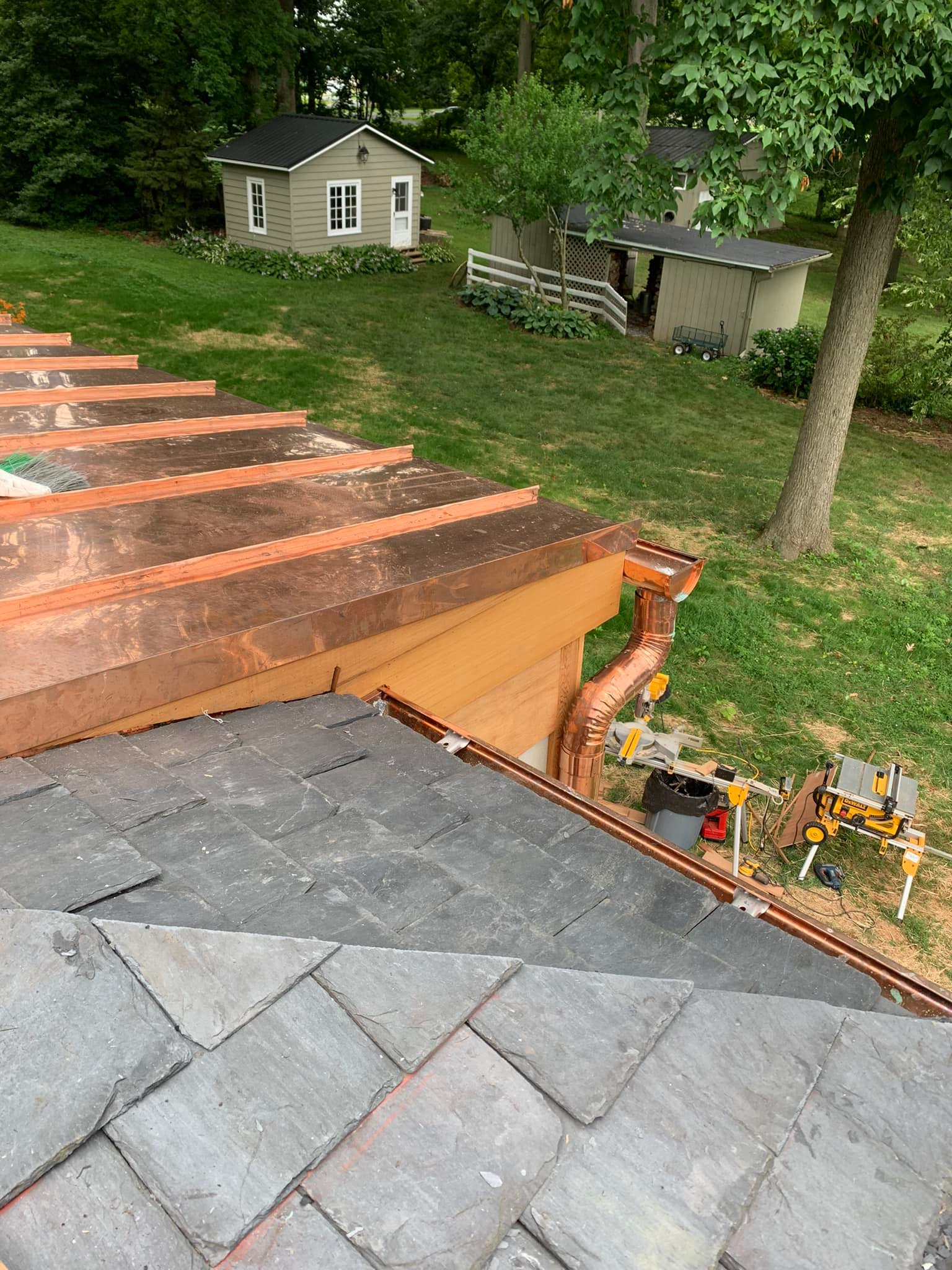 A copper gutter is being installed on the roof of a house.