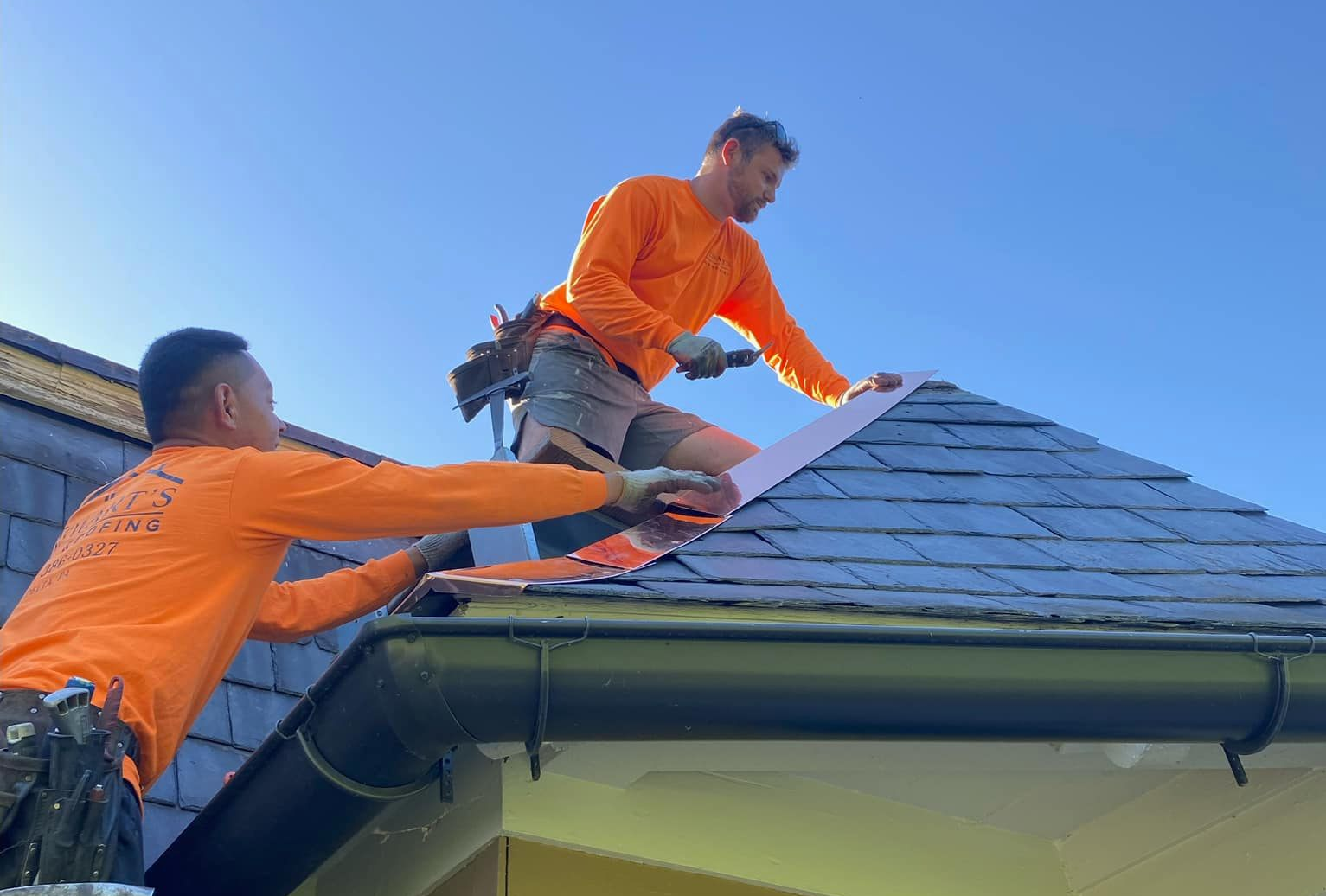 Two men are working on the roof of a house.