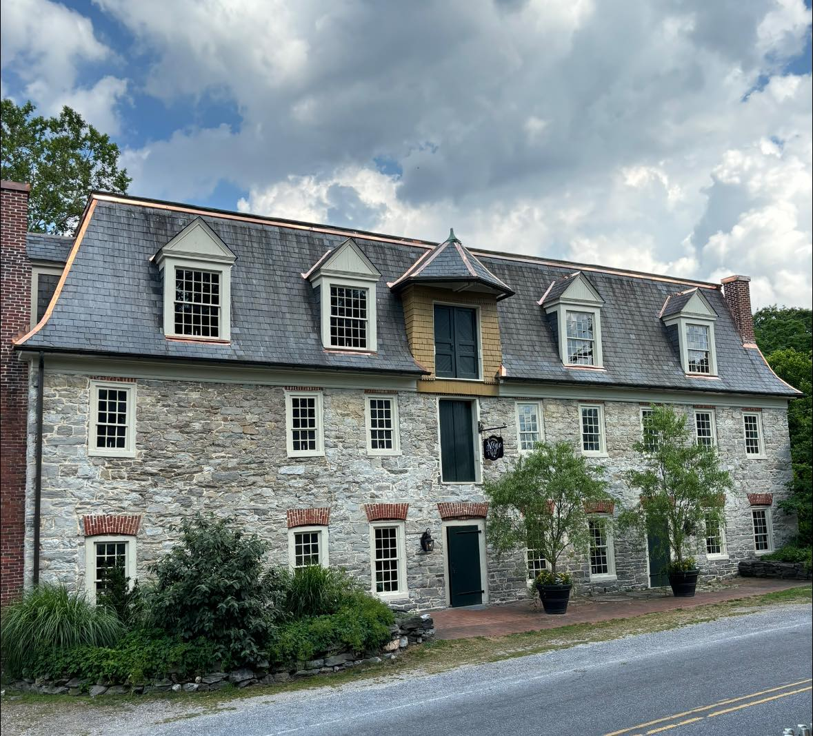 A large stone building with a slate roof is sitting next to a road.