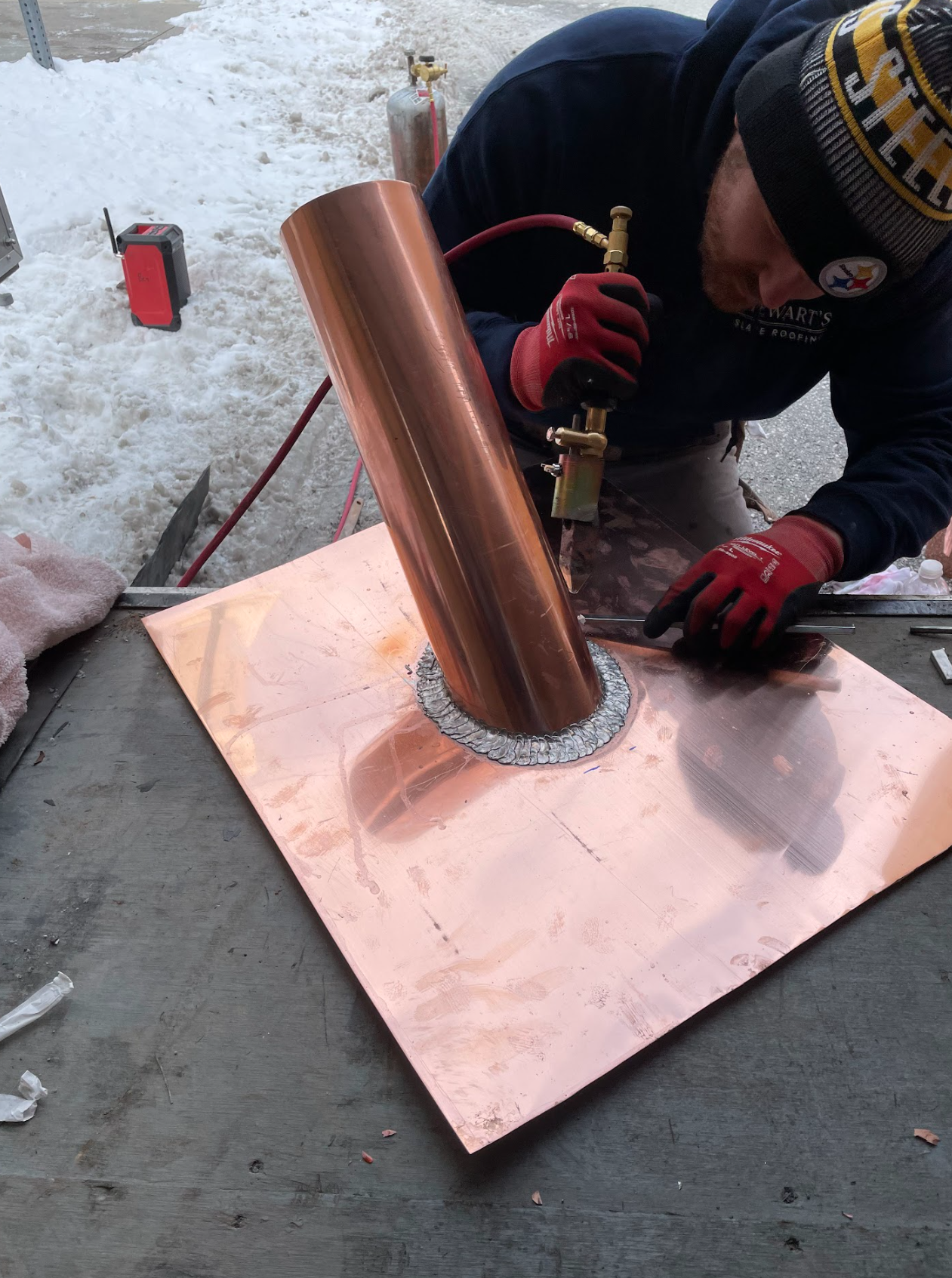 A man is working on a piece of copper with a torch.