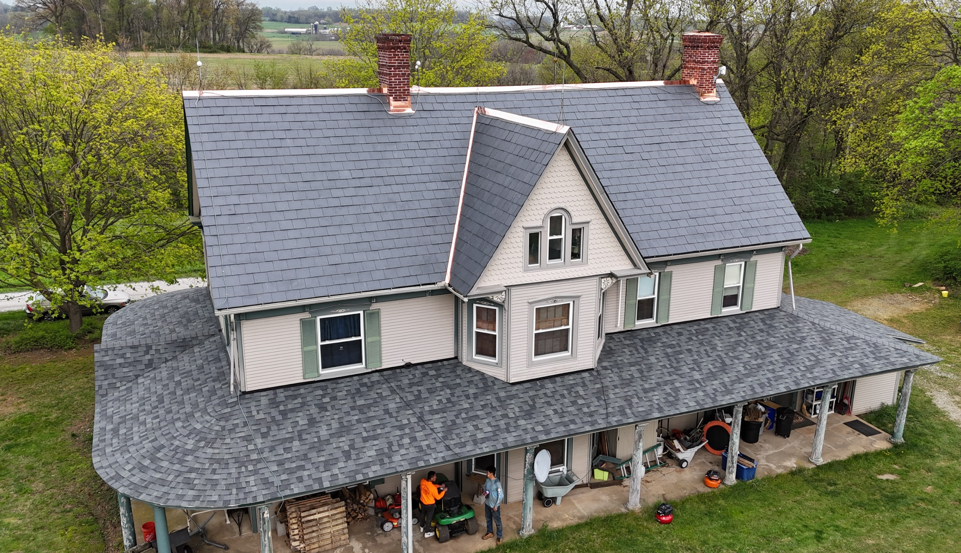 An aerial view of a house with a gray roof and a porch.