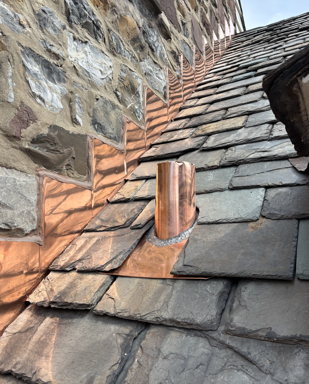 There is a copper pipe on the roof of a building.