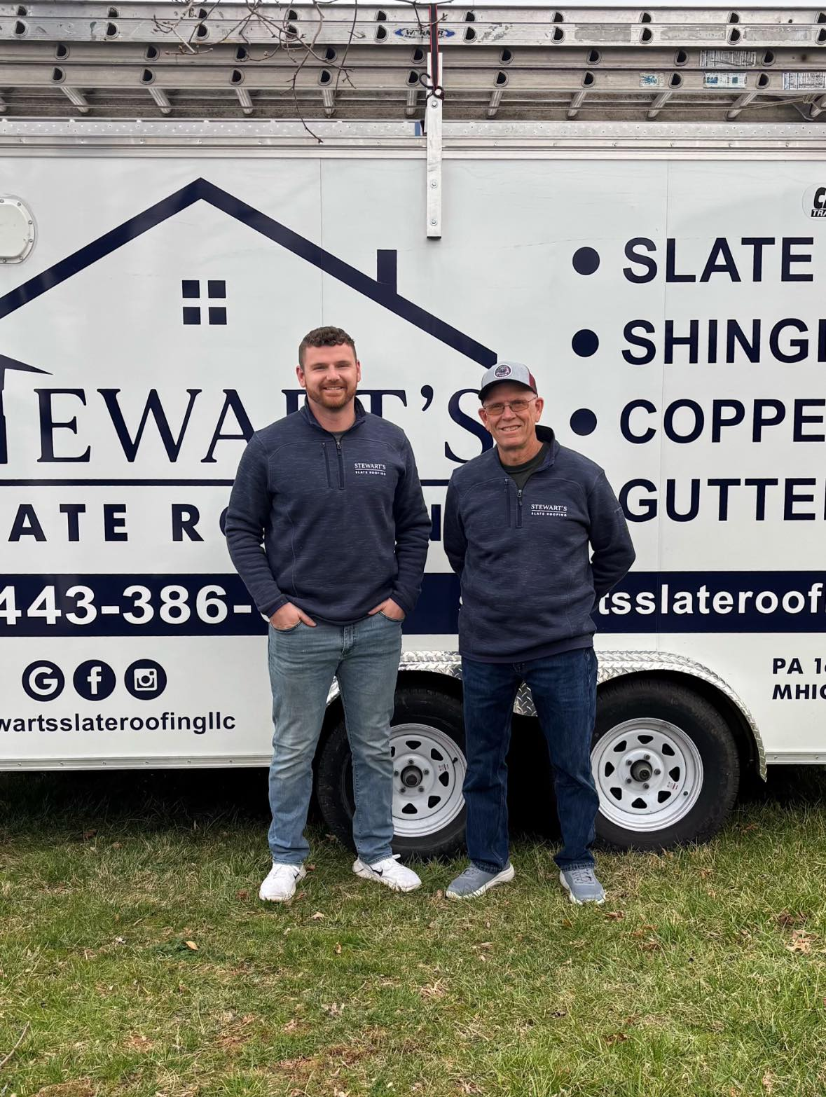 Two men are standing in front of a trailer.