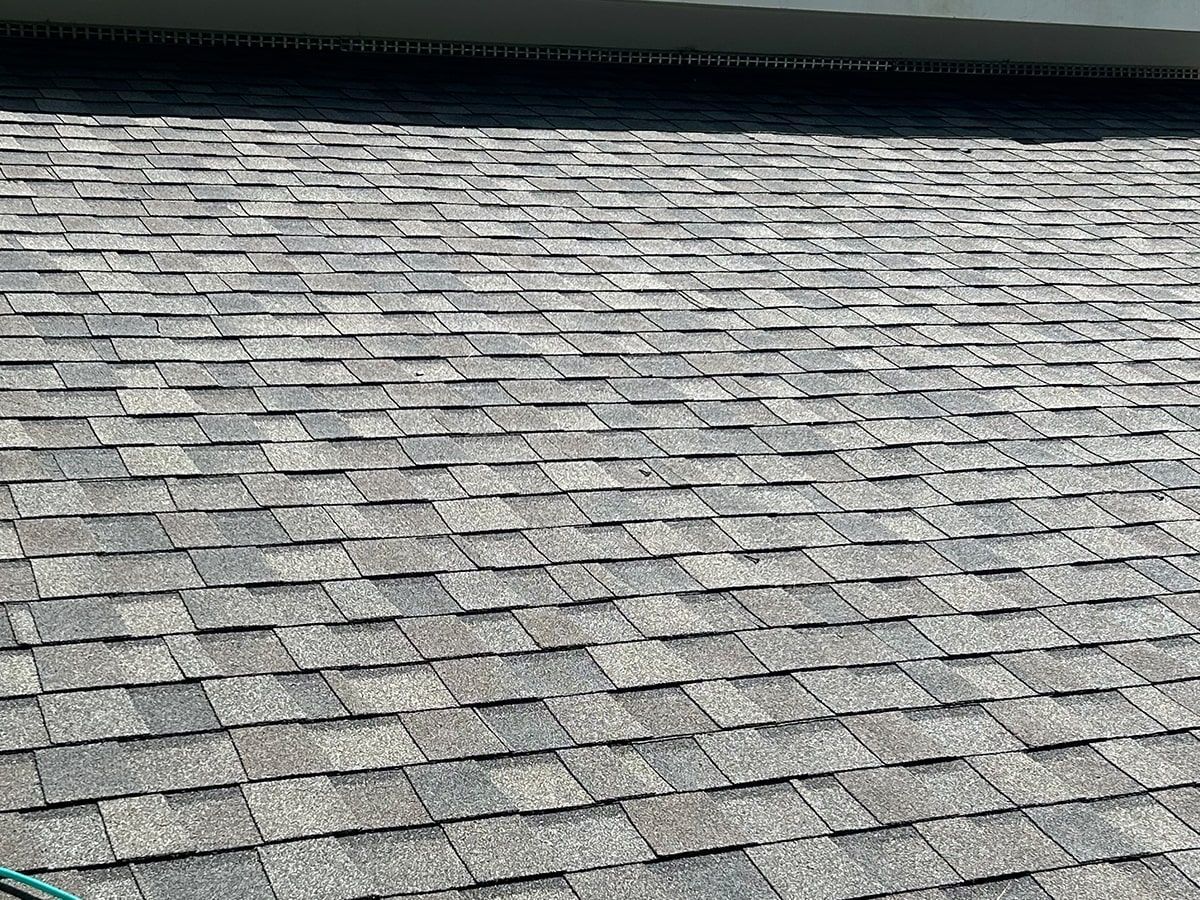 Gray shingled roof with a dark ridge line under a bright sky