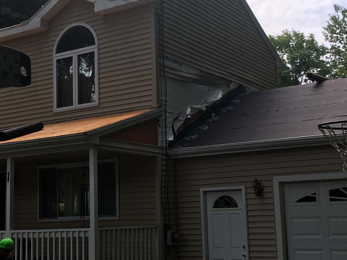 House with damaged roof shingles and dark smoke marks near the garage after fire damage