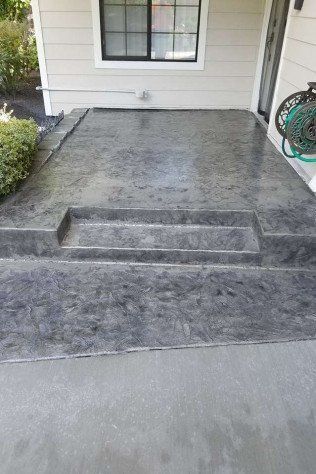A concrete porch with steps and a swing in front of a house.