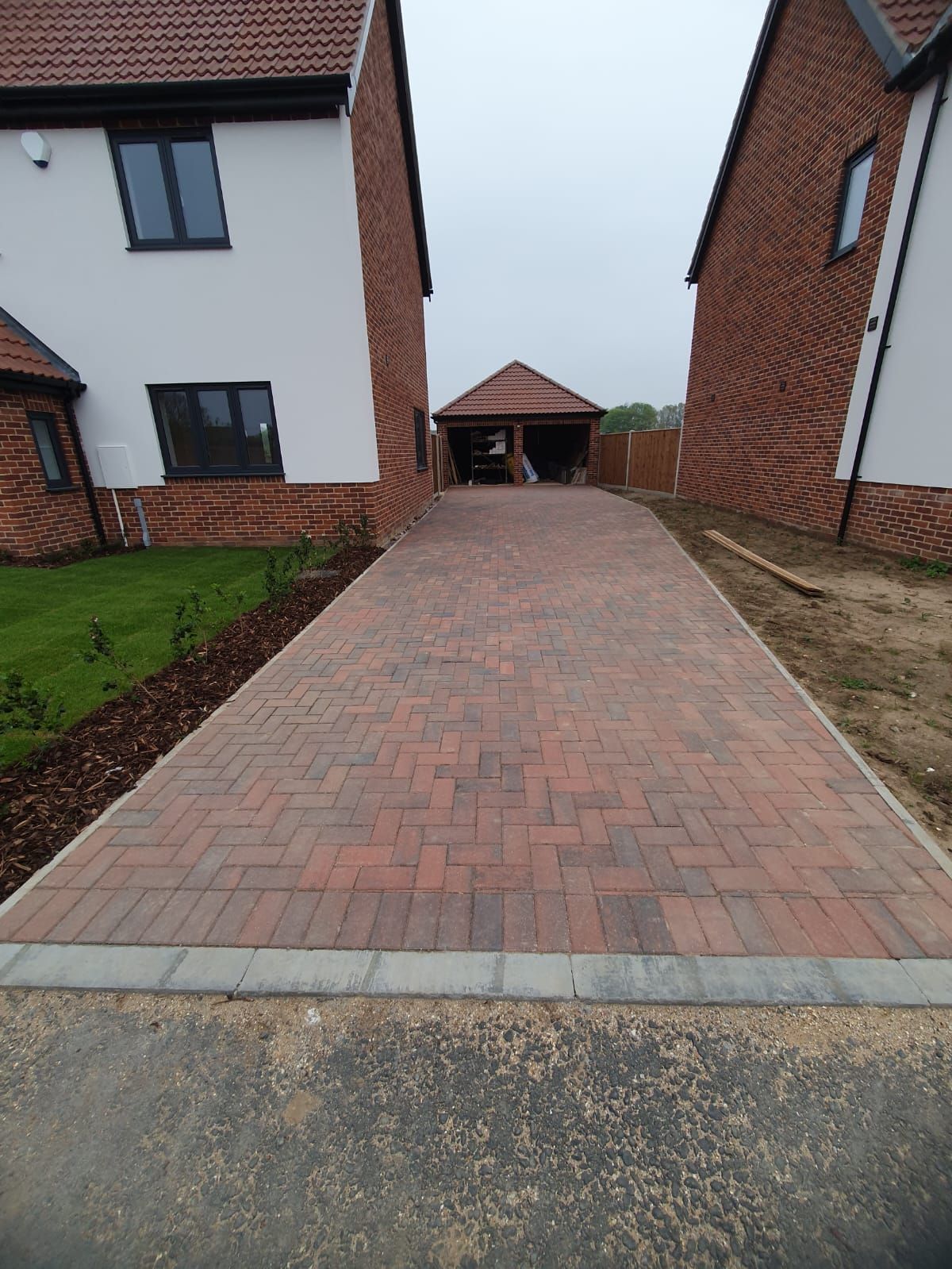 A brick driveway leading to a house with a garage.
