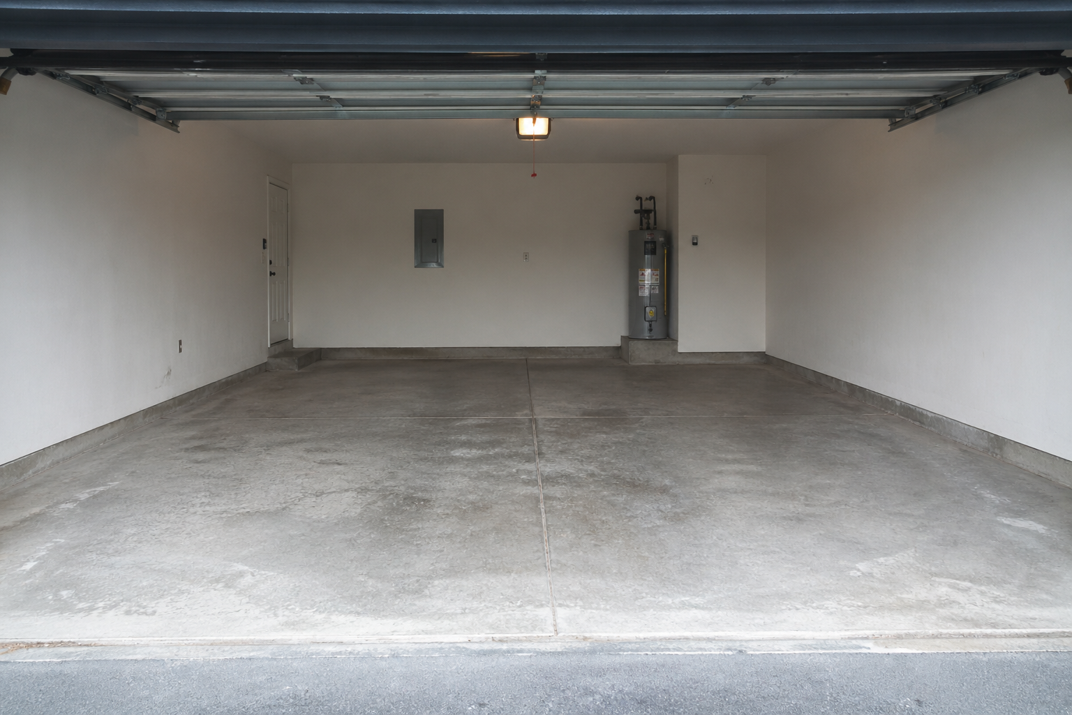Empty two-car garage with concrete floor and closed overhead door