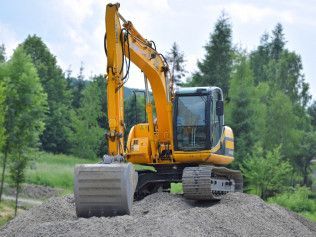 a yellow excavator is sitting on top of a pile of gravel .