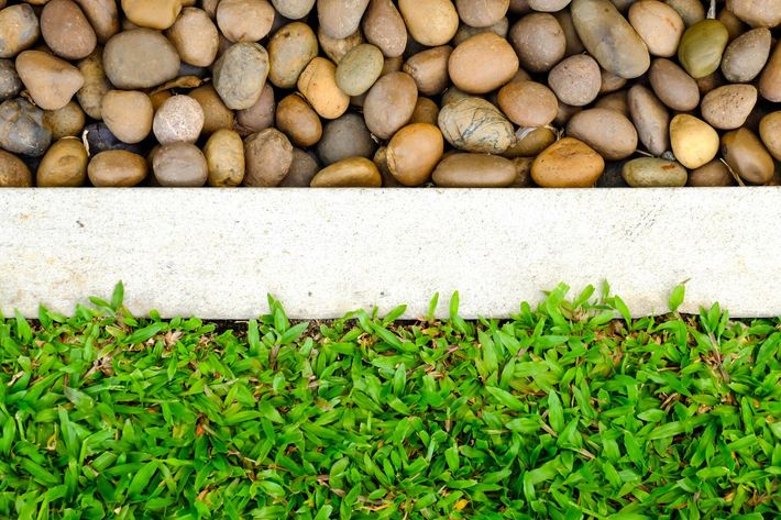 a pile of rocks next to a row of green grass