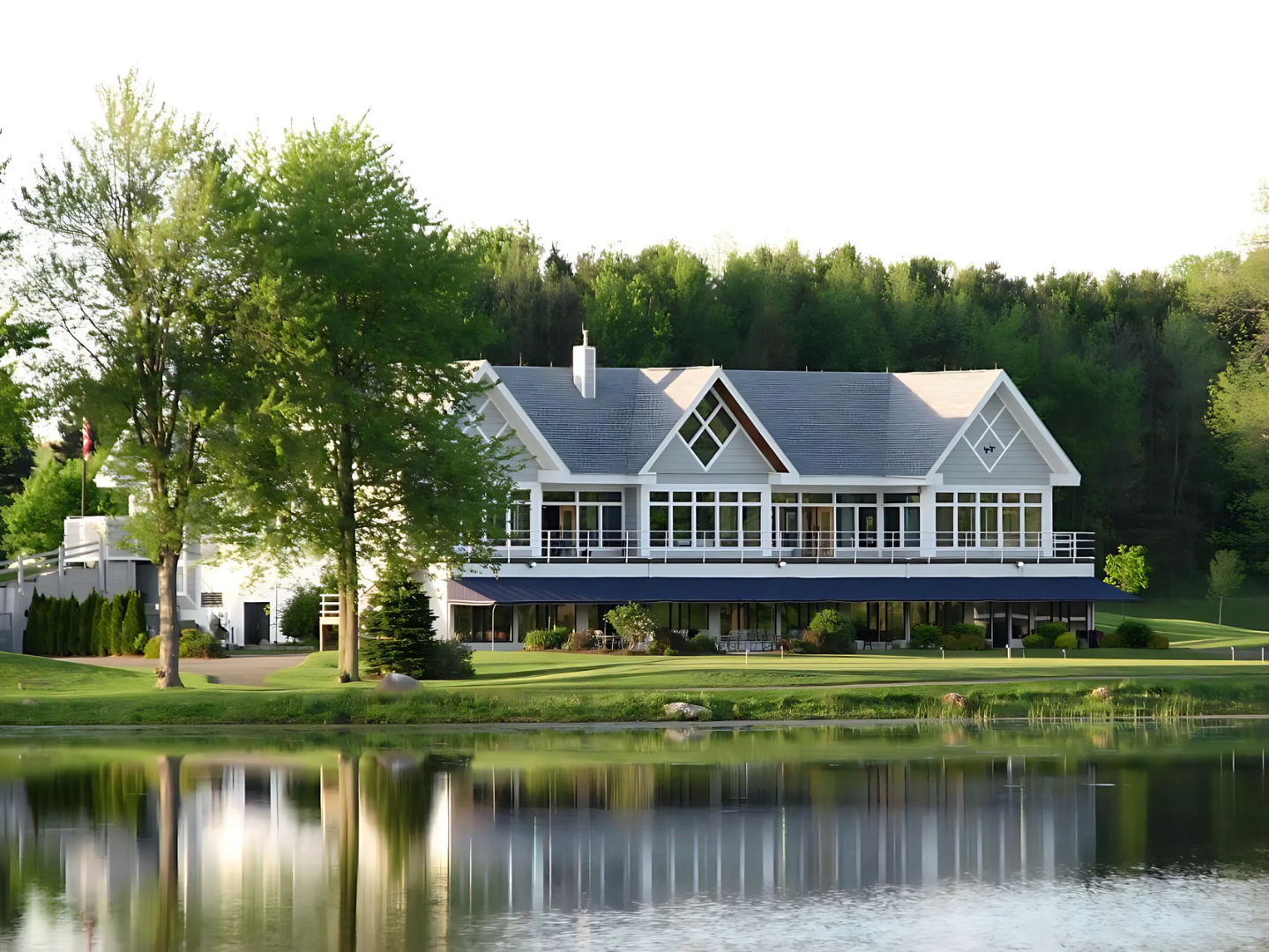 The club house at blue heron hill golf club sits next to a lake surrounded by trees