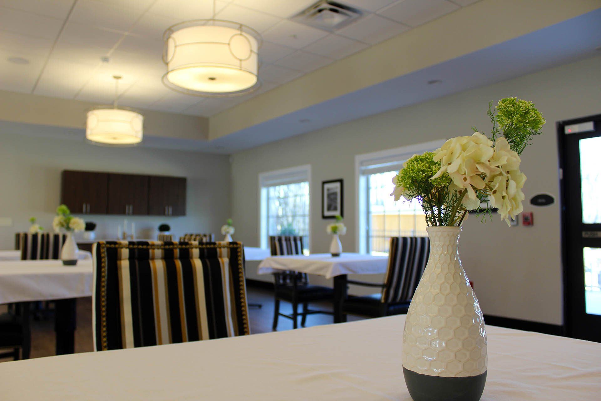 A vase of flowers sits on a table in a dining room.