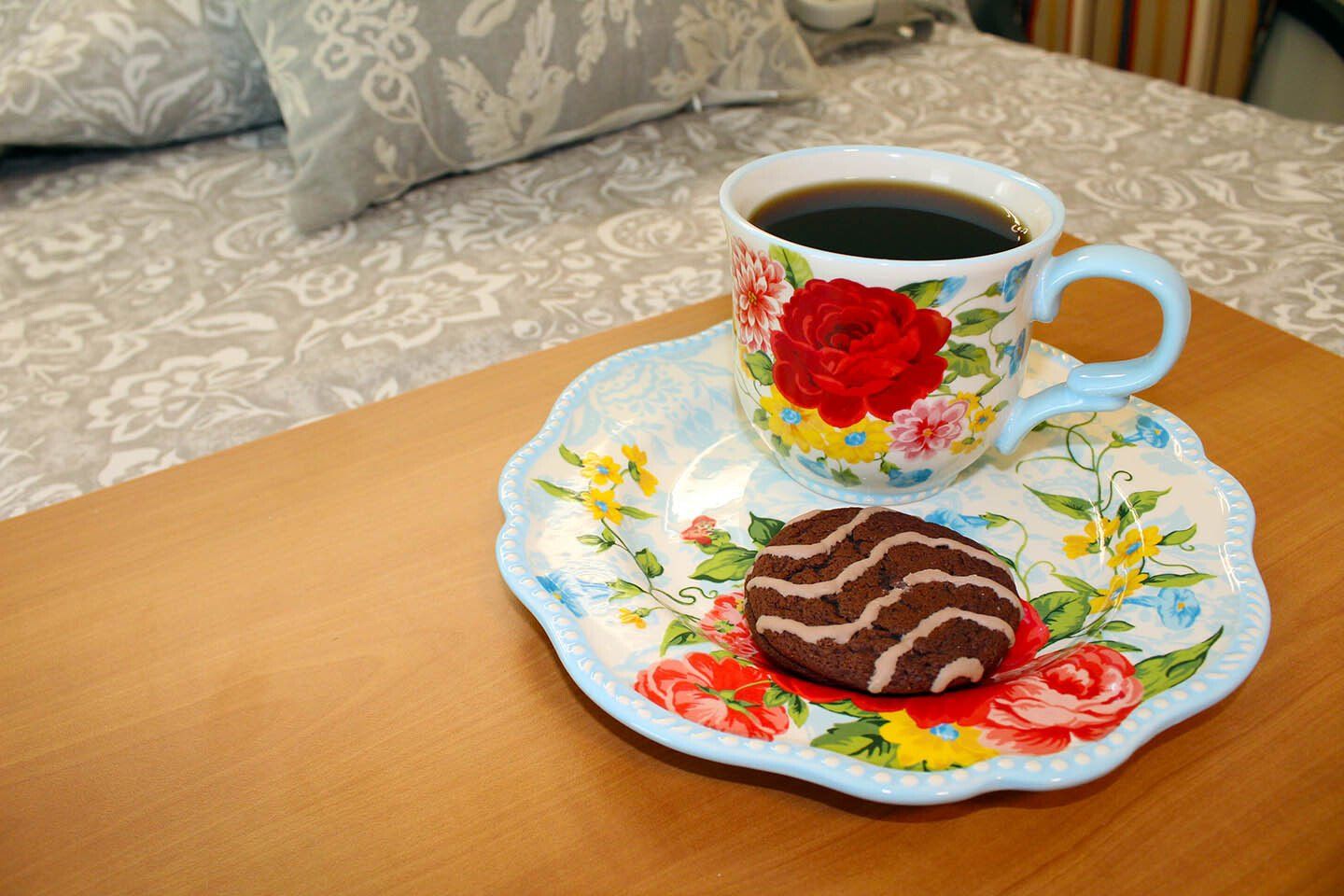 A cup of coffee and a cookie on a saucer on a table.