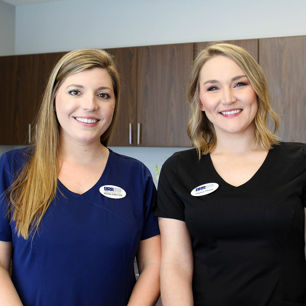 Two women are standing next to each other and smiling for the camera.