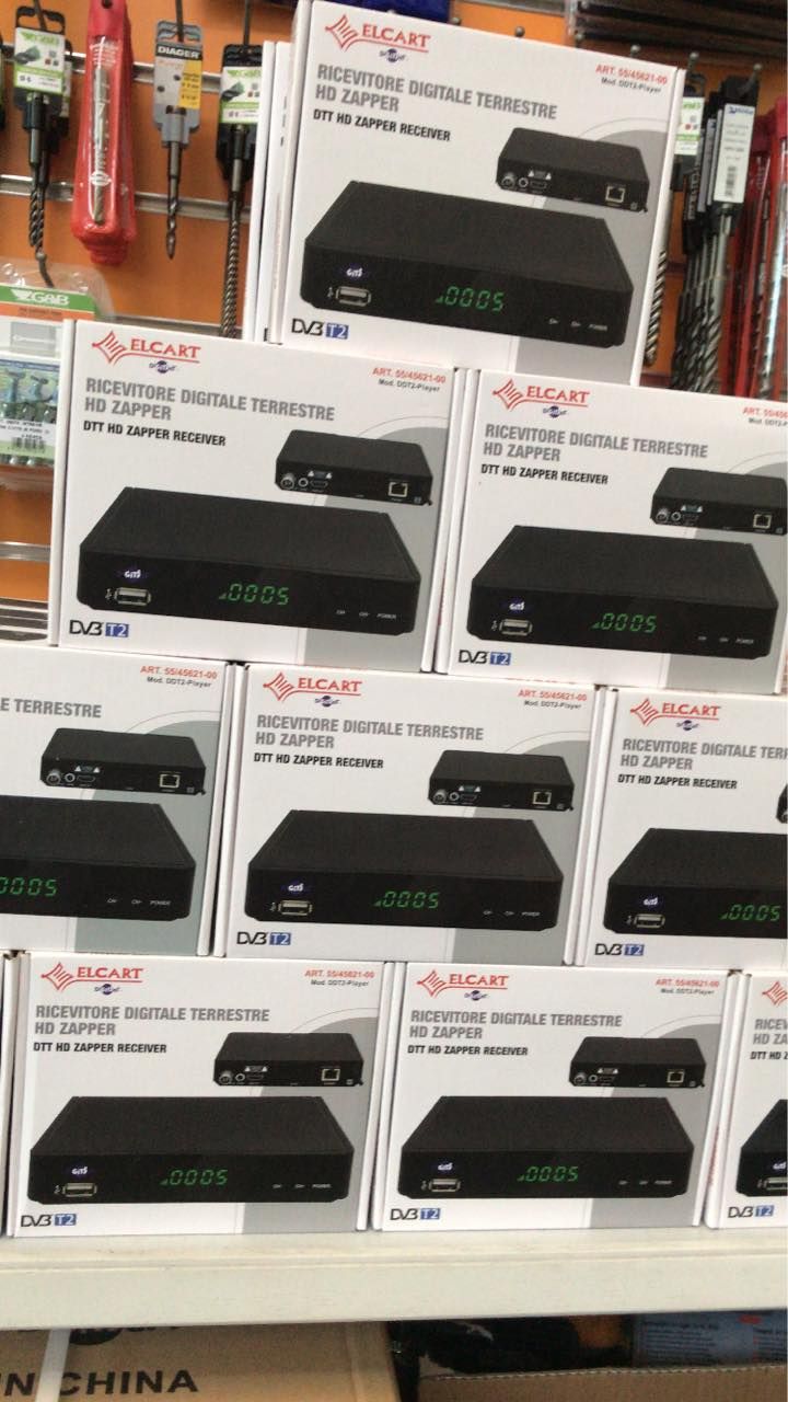 Scatole di decoder digitali impilate sullo scaffale di un negozio, che mostrano l'immagine e le caratteristiche del prodotto.