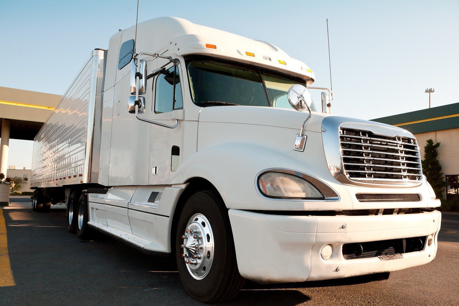 A semi truck with a flat bed is driving down a highway.
