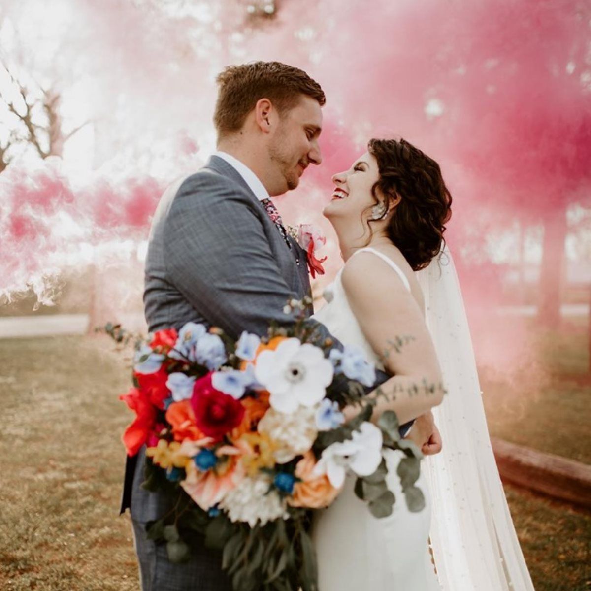 A bride and groom are standing next to each other holding a bouquet of flowers.