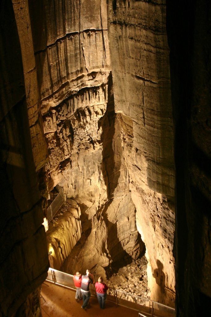 A couple of people are standing in a cave.