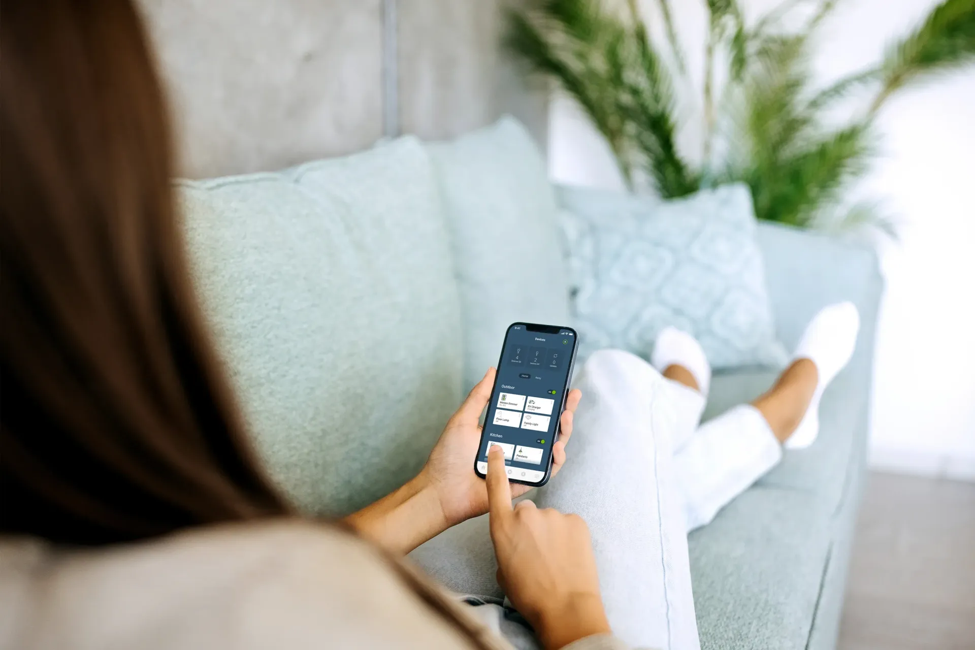 Person using a smartphone while reclining on a light blue sofa with pillows