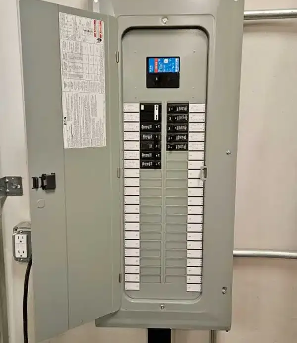 Open electrical breaker panel with rows of labeled switches and a small display screen