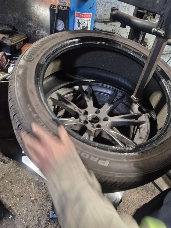 Hand holding a tire over a wheel rim in a workshop