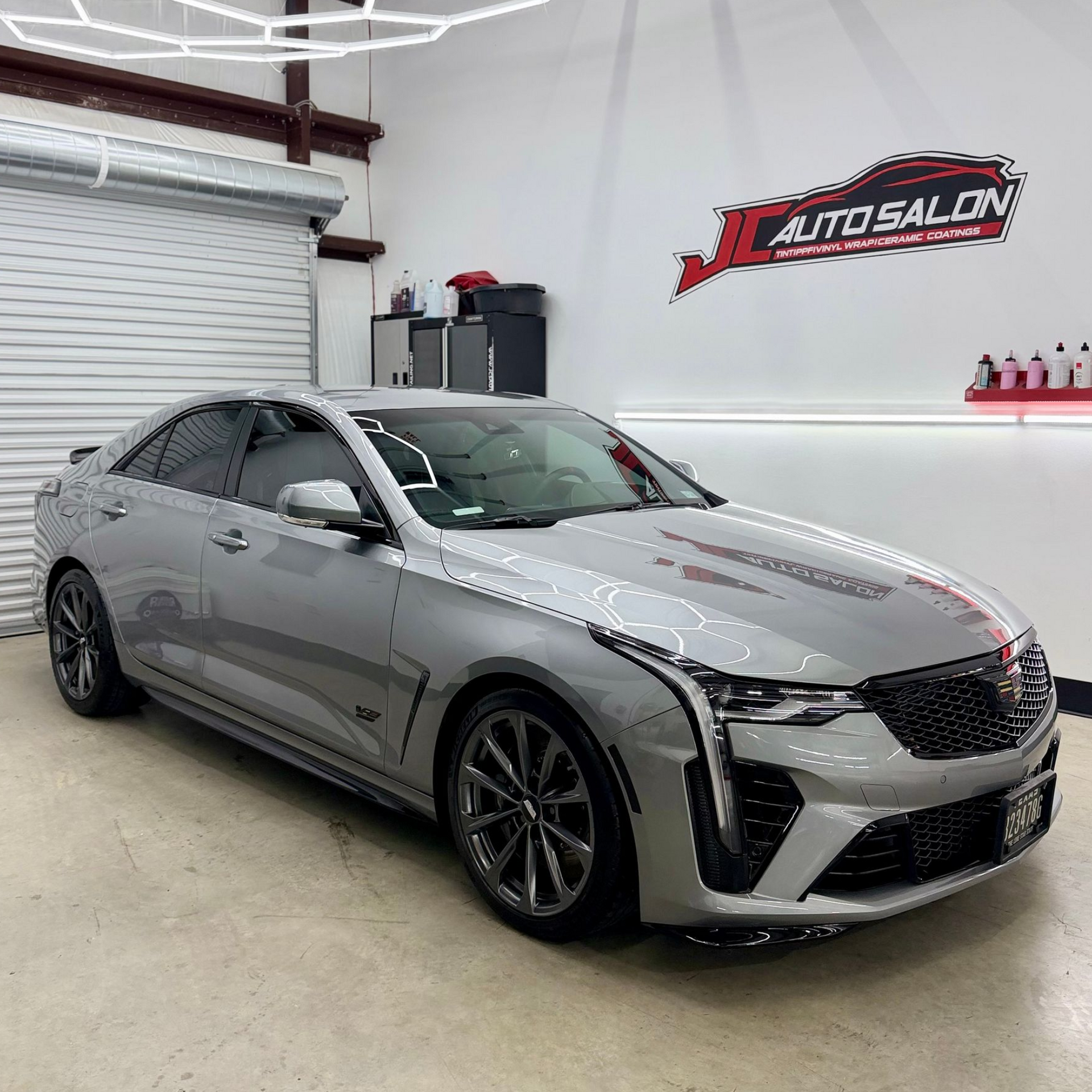 Silver sedan in an auto showroom, parked on a polished floor with a wall logo in the background