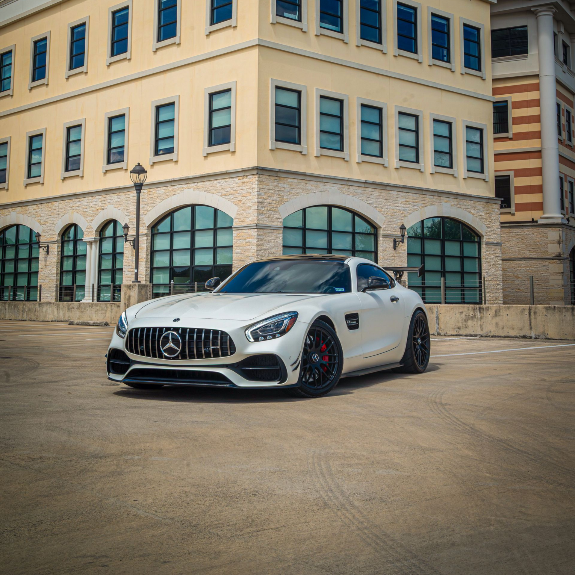 White sports car in a bright garage showroom with glossy black roof and wall signage