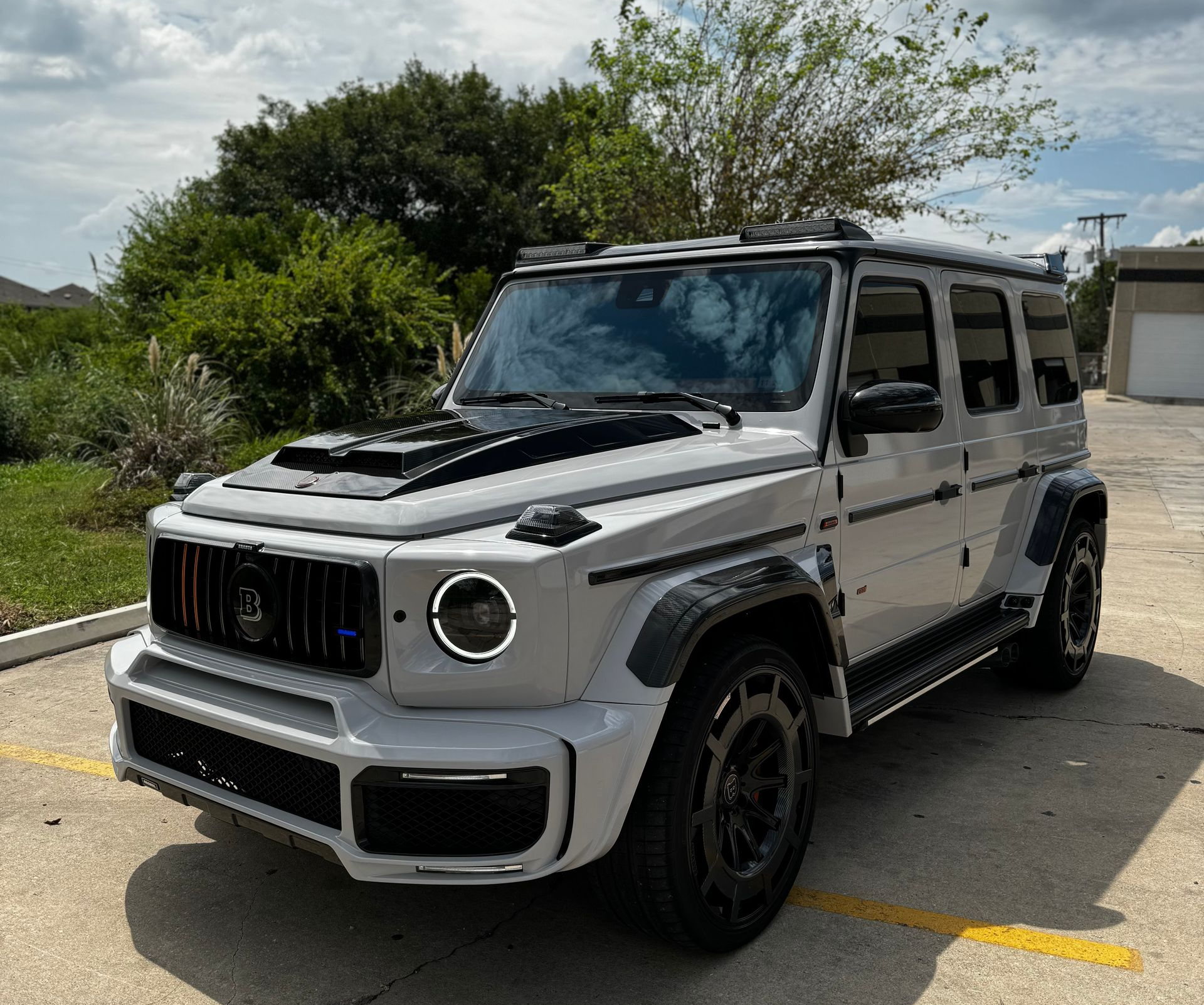 Silver off-road SUV parked in a lot under a cloudy sky, with black trim and tinted windows.