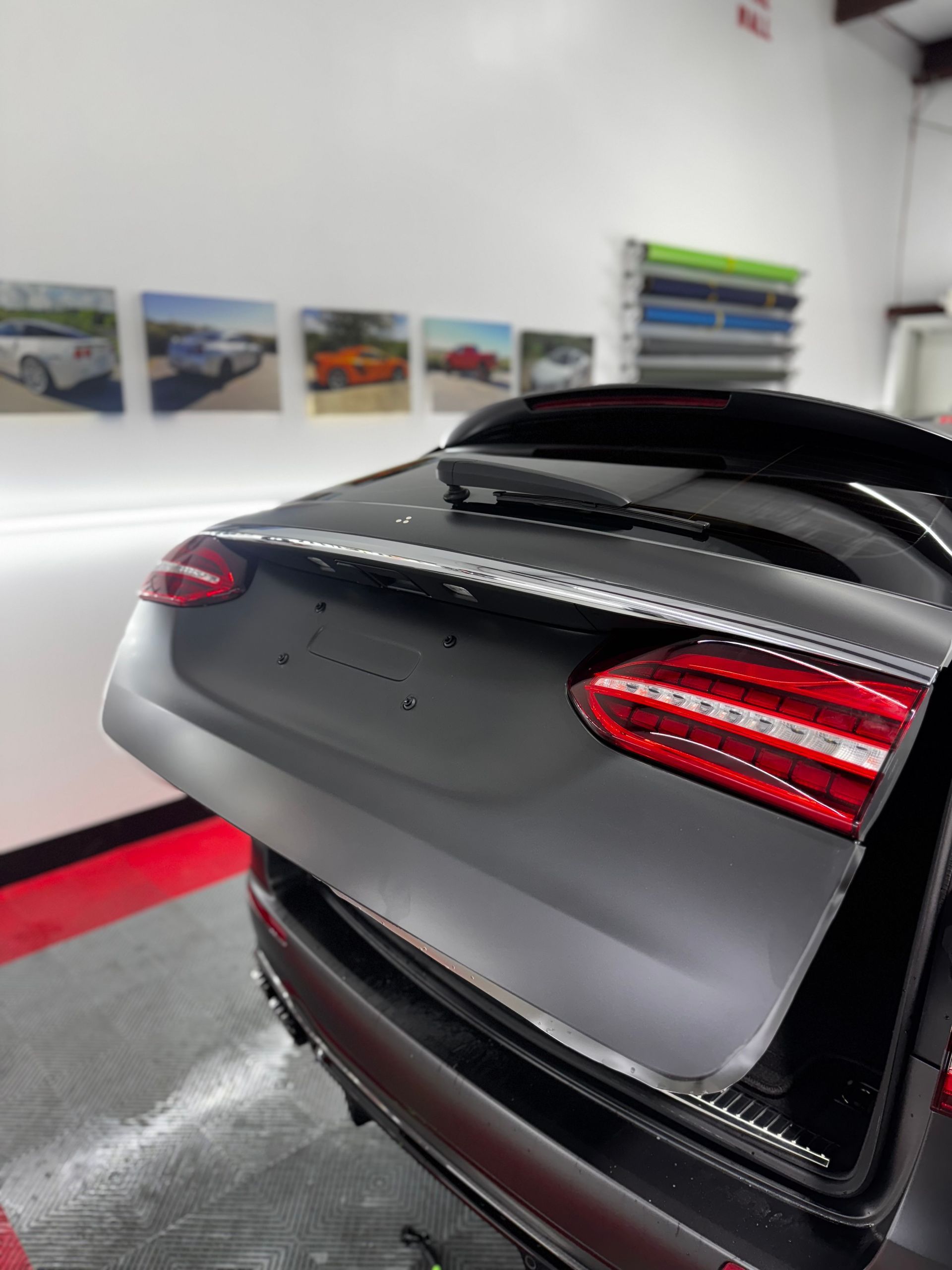 Rear view of a black sports car in a showroom, with red taillights and a glossy finish.
