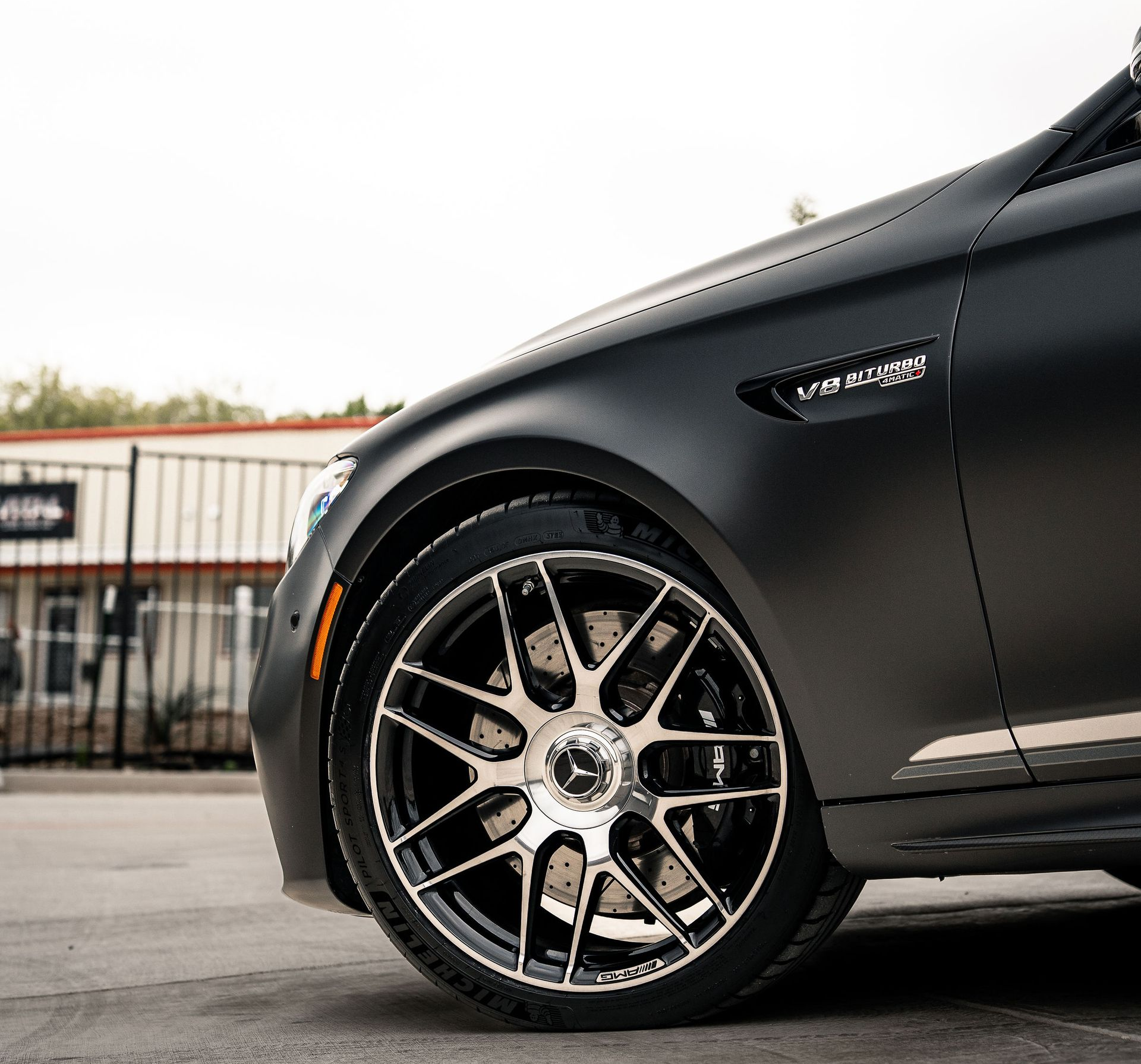 Black sports car with chrome rims parked on a street near a building