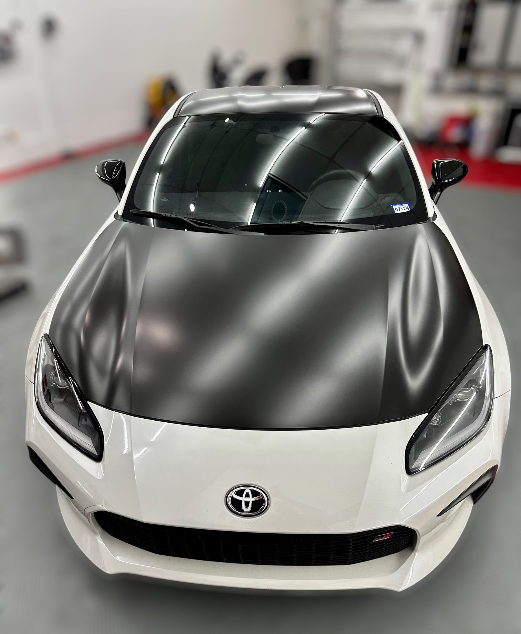 Blue sports car with black racing stripes parked in a garage