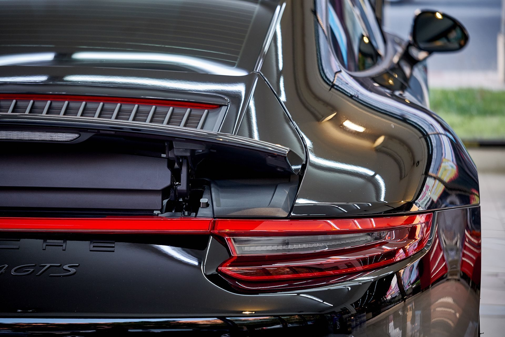Rear view of a black Porsche 911 GT3 in a showroom, showing its taillights and rear wing