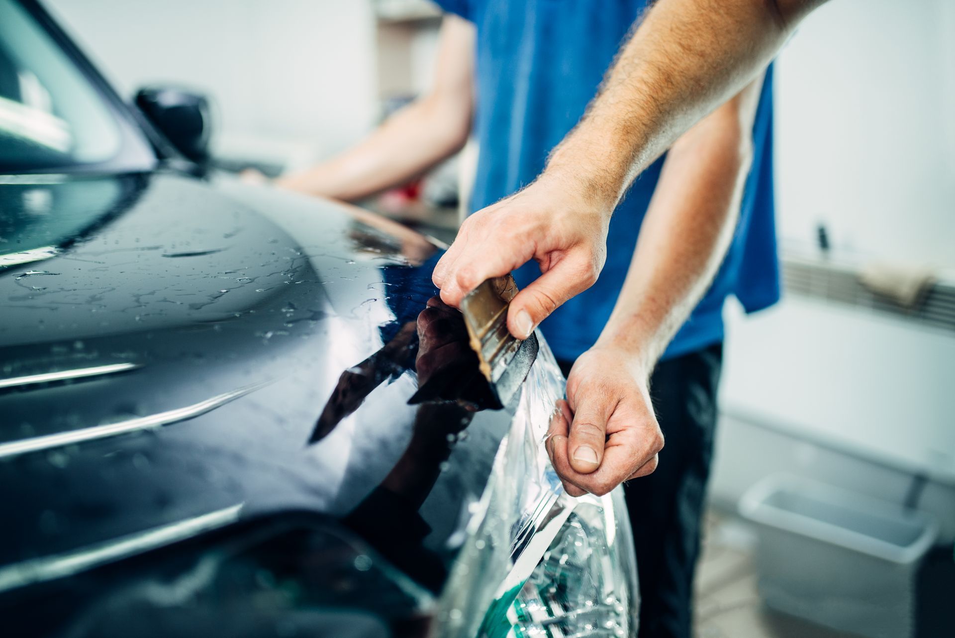 Person polishing a black car with a microfiber cloth at a car wash
