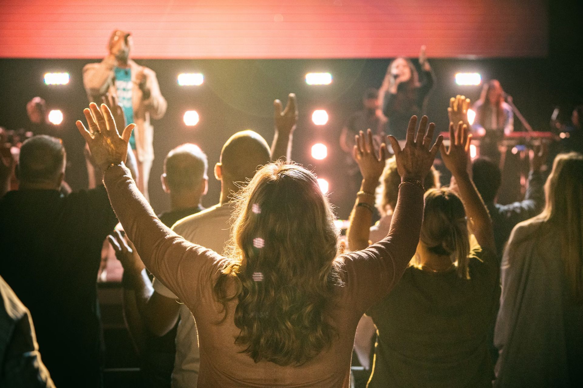 A group of people are standing in front of a stage with their hands in the air.