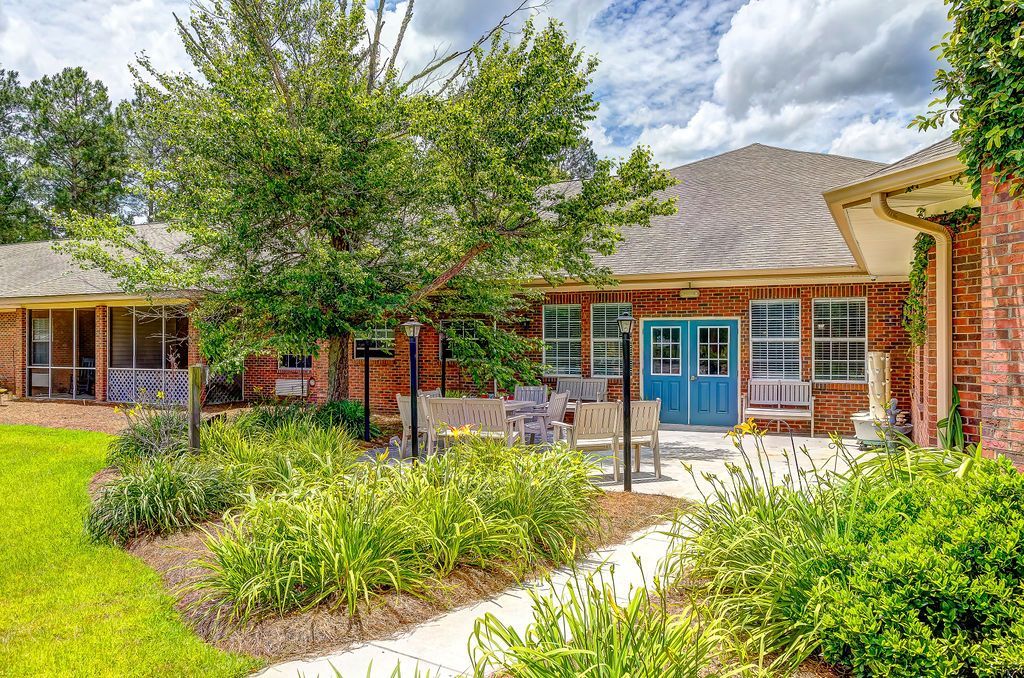 Courtyard of a brick building with blue doors, trees, and landscaped greenery under a cloudy sky