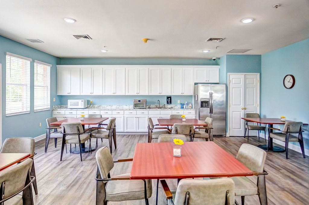 Bright dining room with blue walls, white cabinets, tables, and chairs under ceiling lights