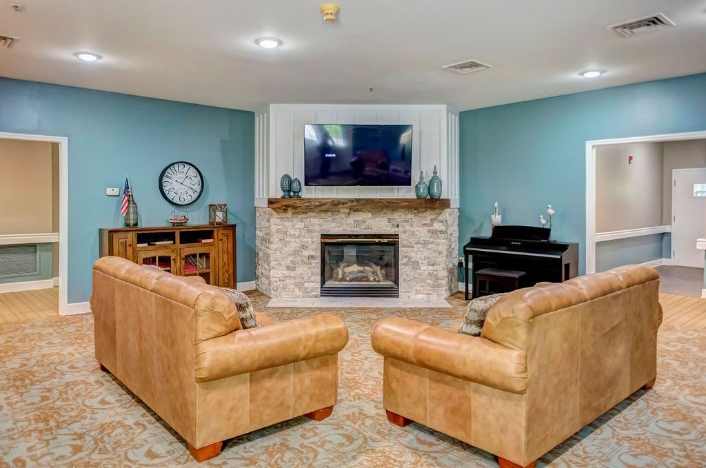 Living room with tan sofas, blue walls, fireplace, and wall-mounted TV