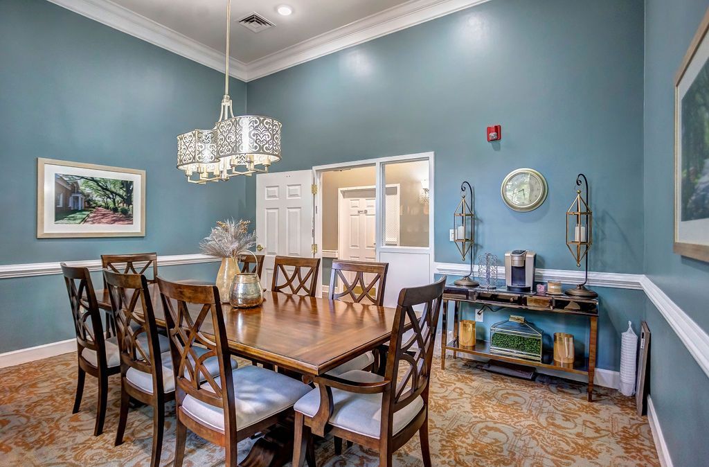 Blue dining room with wooden table, patterned chairs, chandelier, and sideboard against light blue walls