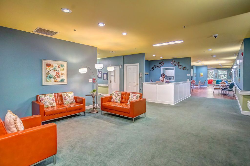 Bright hotel lobby with orange couches, teal walls, and a reception desk in the background