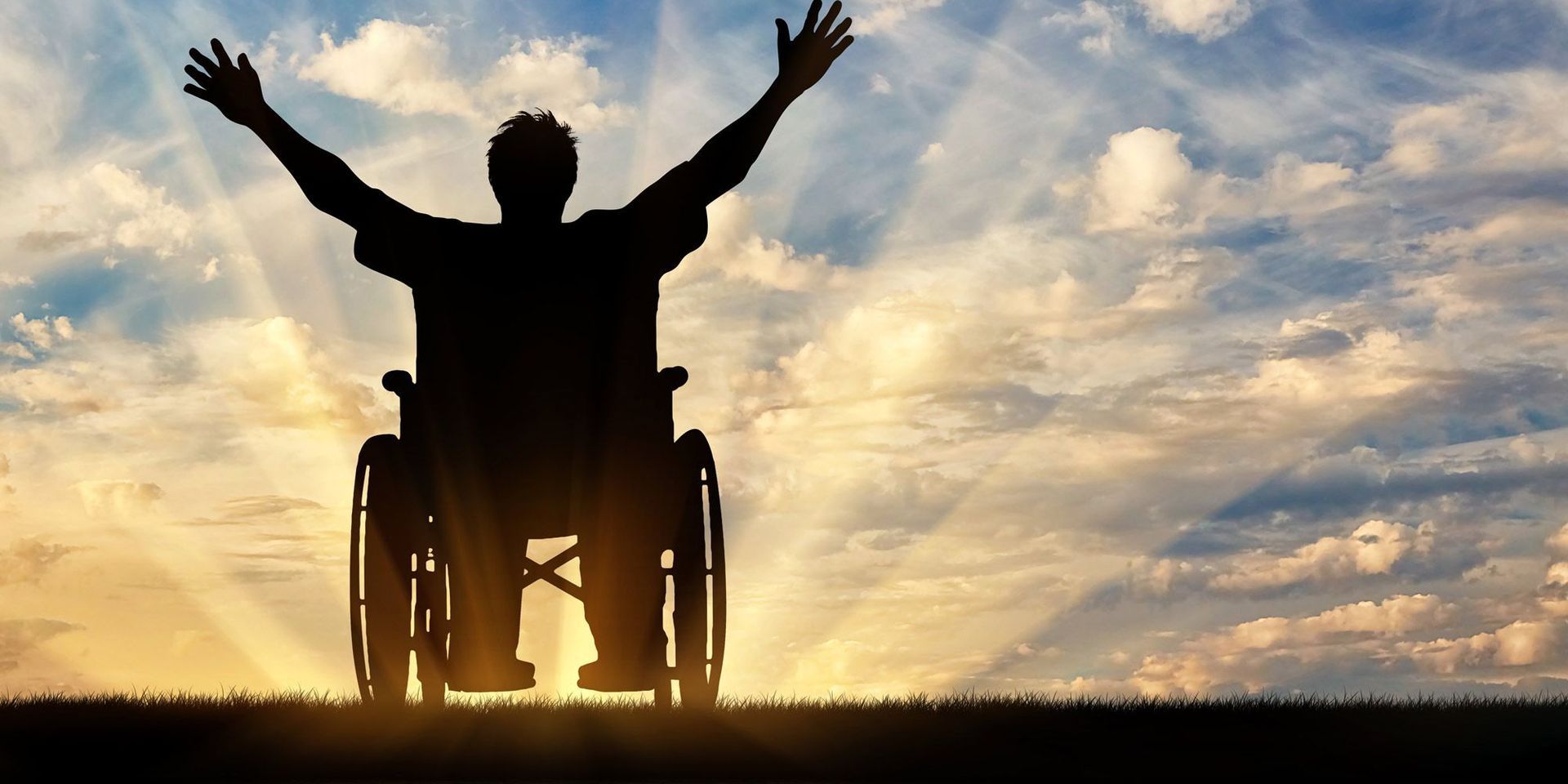 A man in a wheelchair is raising his arms in the air.