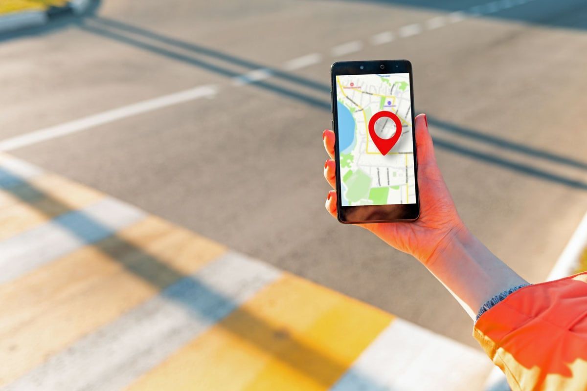 Photo of a person is holding a cell phone with a local search map on it.