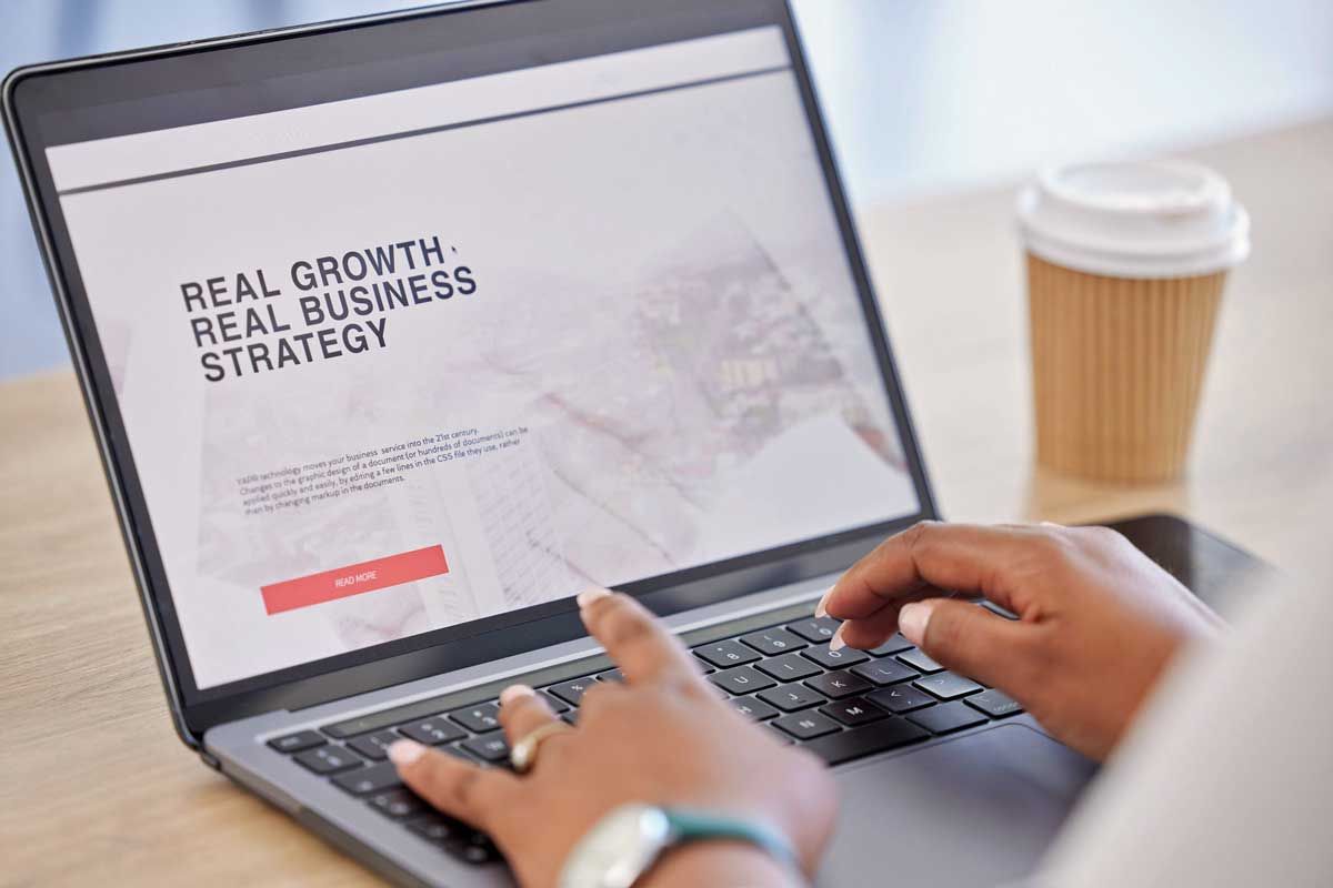 A pair of hands typing on a laptop displaying the text 