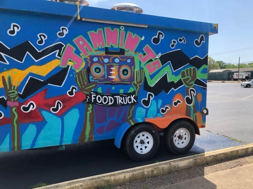 Colorful food truck mural with music notes parked beside a curb in a lot