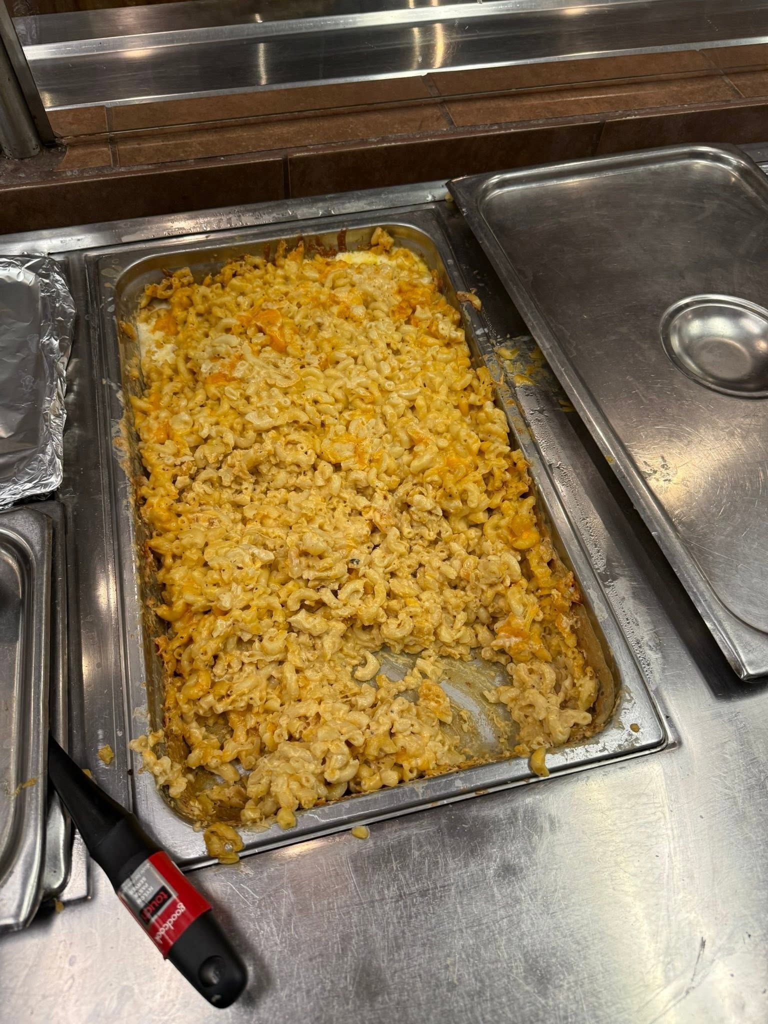 Trays of fried rice on a cafeteria serving line, with a serving spoon in the foreground.