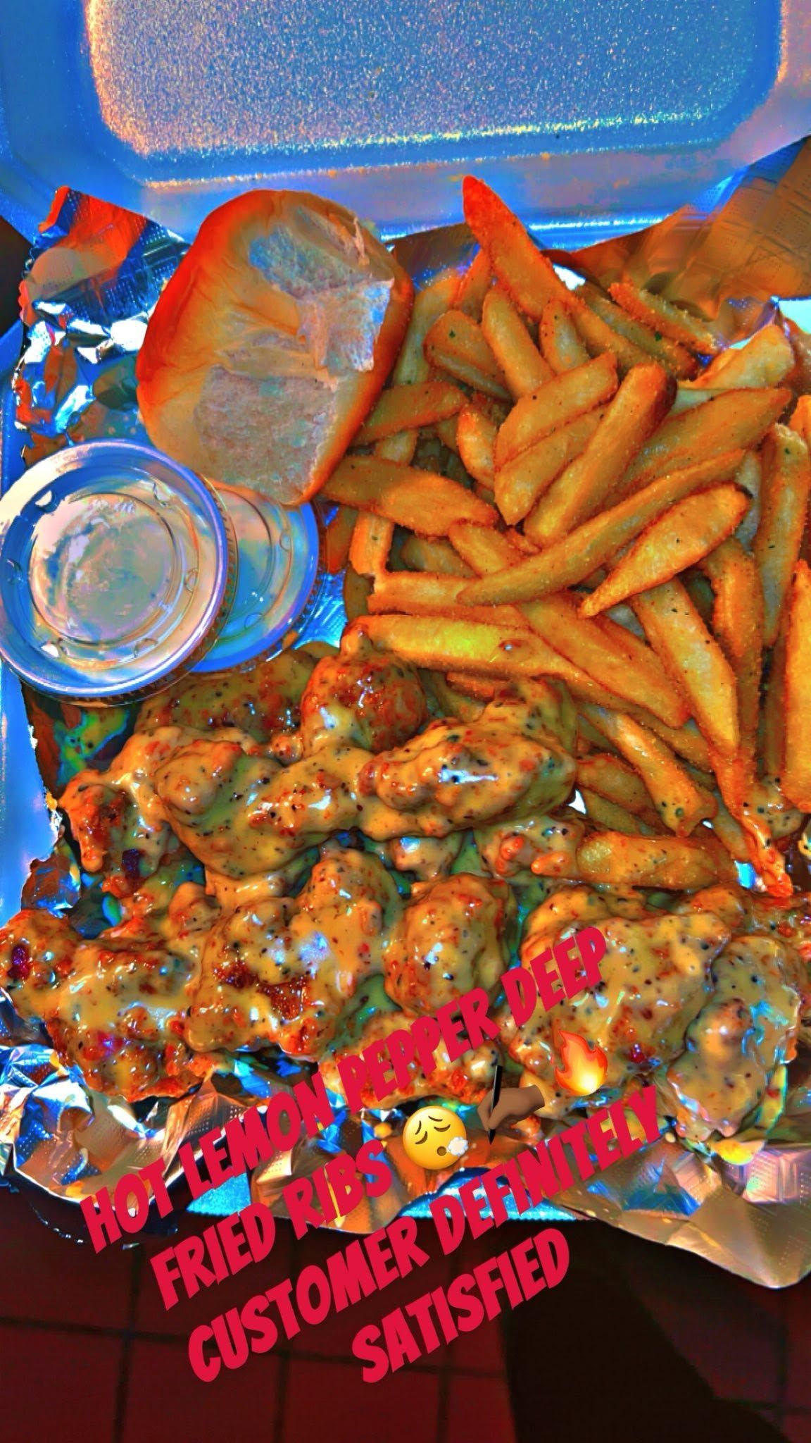 Takeout container with fries, grilled meat, bread, and a drink cup inside a blue box