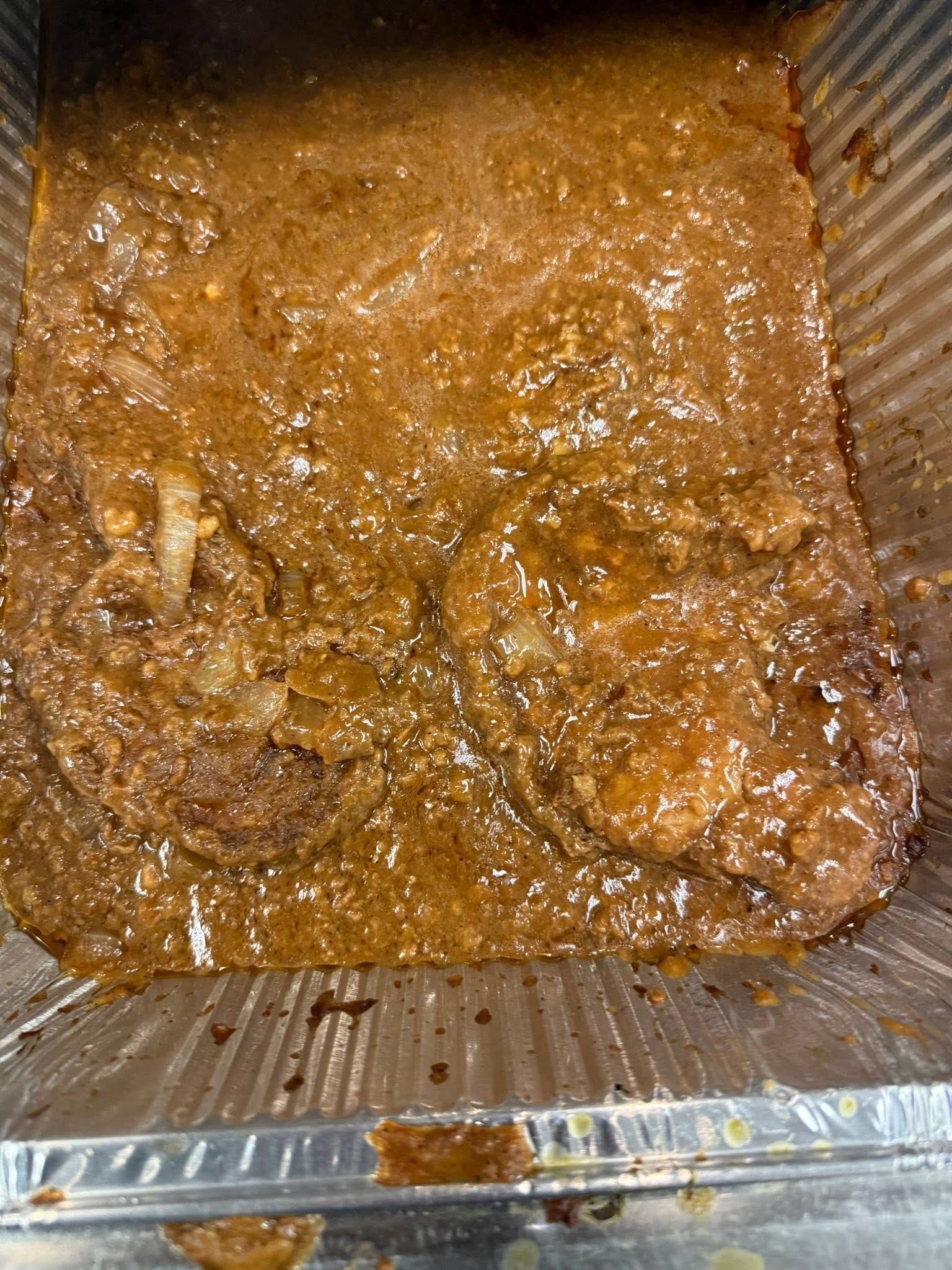 Brown saucy food in a clear rectangular container, viewed from above