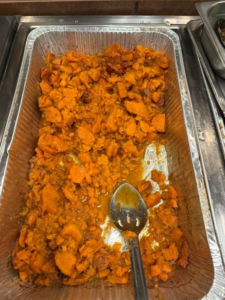Tray of orange diced food in a buffet pan with a serving spoon