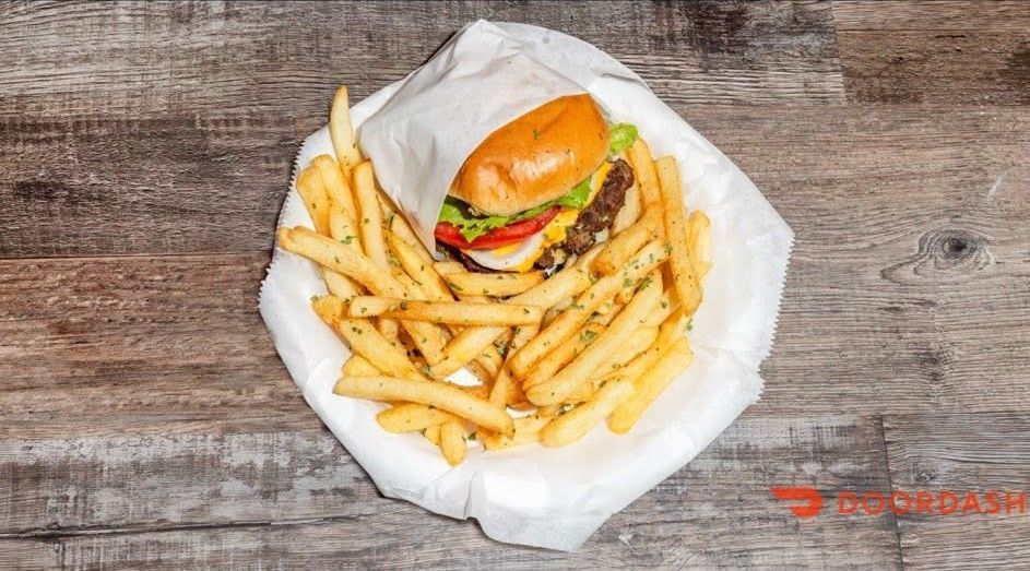 Burger and fries in a white wrapper on a wooden table