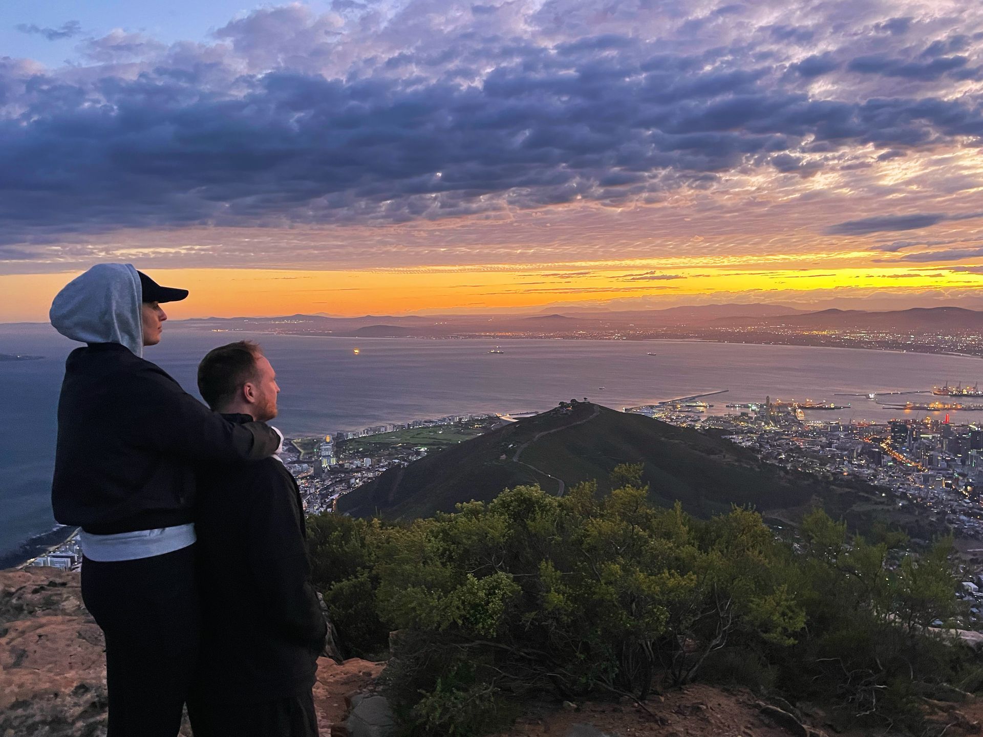 Couple enjoying sunset views over Cape Town from the mountain